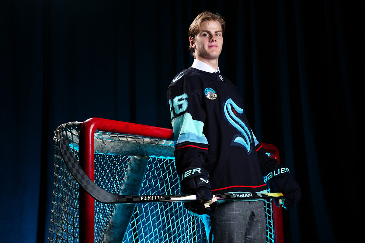 Casey Mutryn posing next to a goal post with a Kraken jersey on