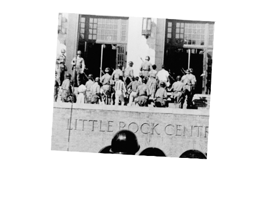 Members of the. military stand infront of a school with school children.