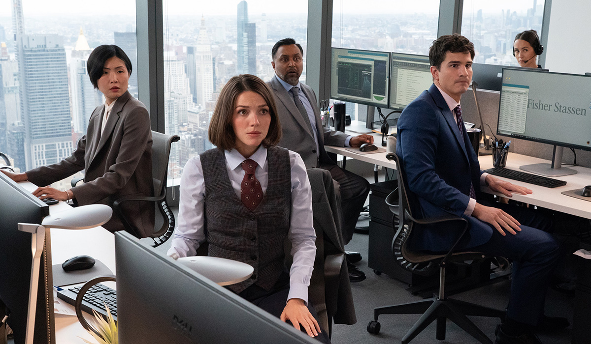 Three women and two men sit at cubicles.