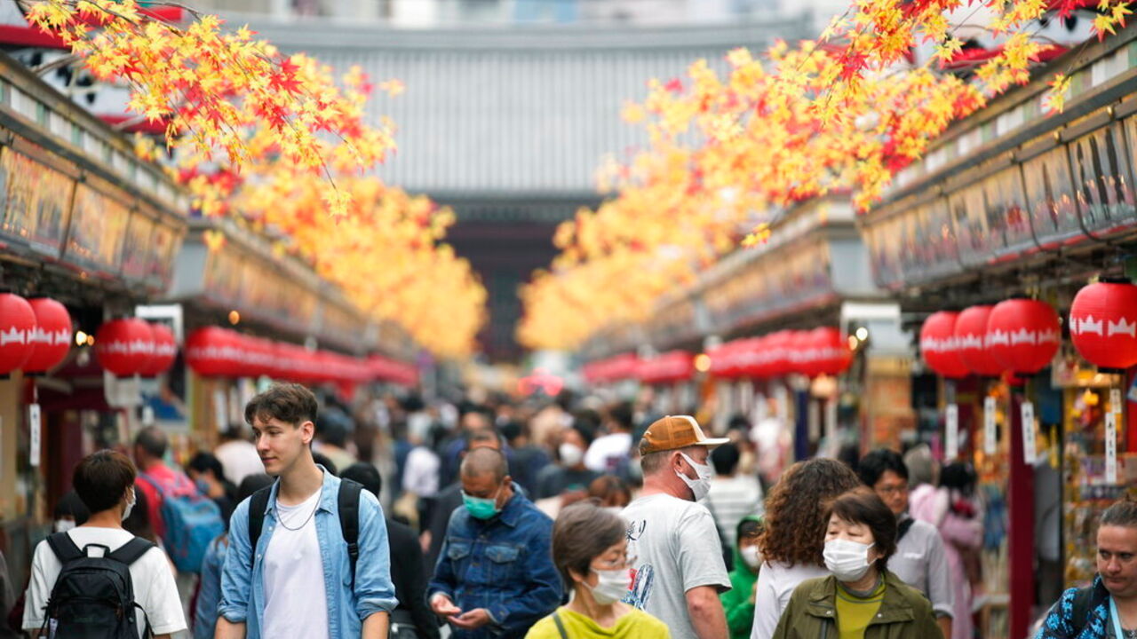 Tourists walk down a promenade leading to the Sensoji Buddhism temple.