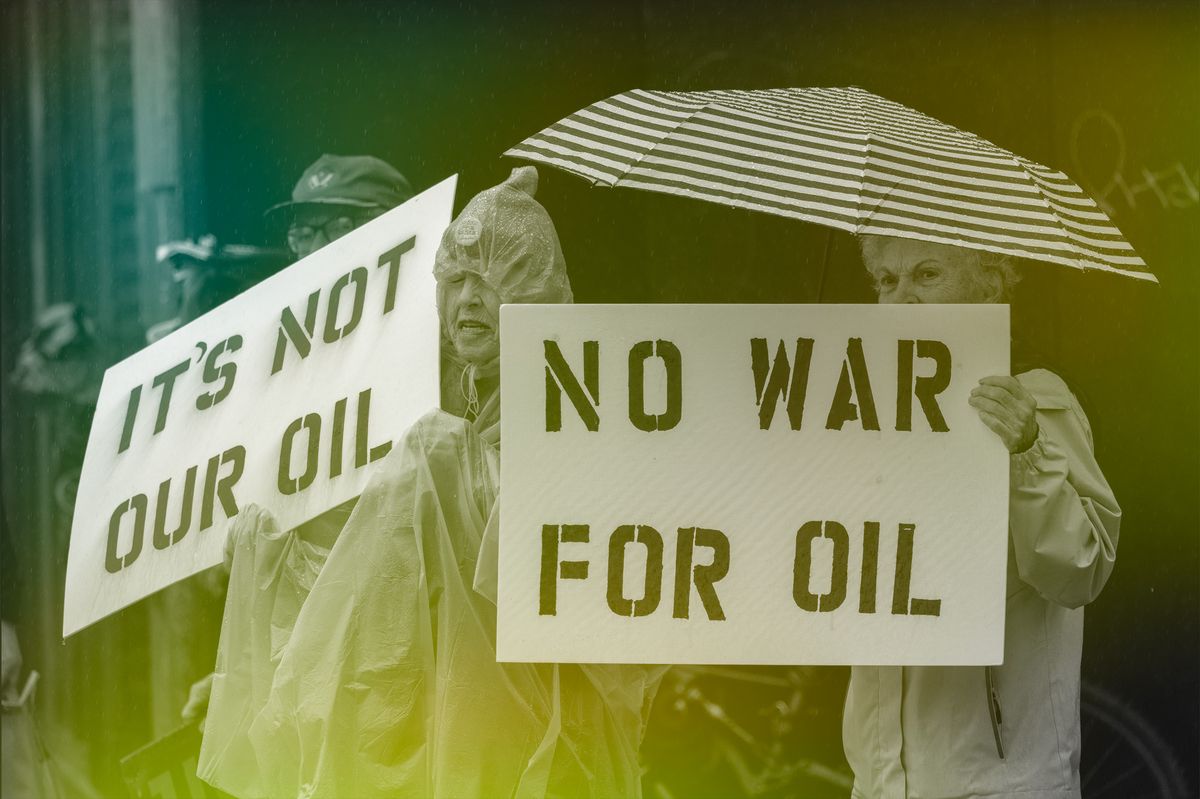 Protesters hold signs opposing going to war over oil.
