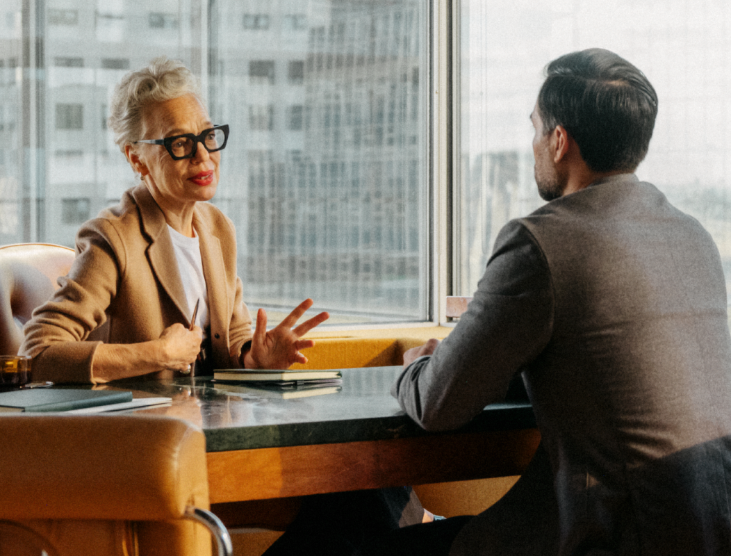 Photo of women interviewing a man sitting across a desk in office building