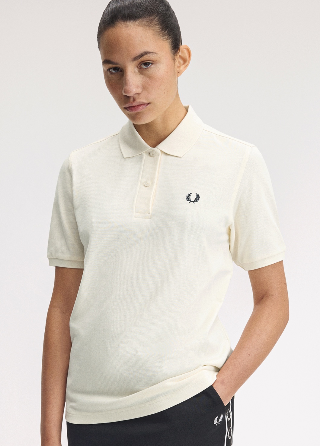 A female model wears a one-colour Fred Perry polo in ecru