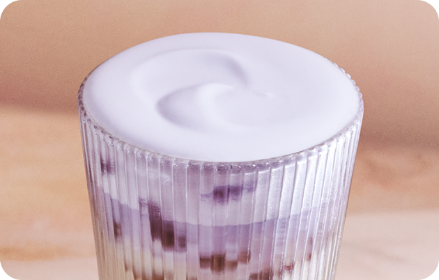A close-up of a cold drink topped with Lavender Cold Foam.