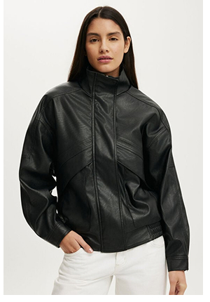 Woman wearing a black leather jacket and white pants against a white background
