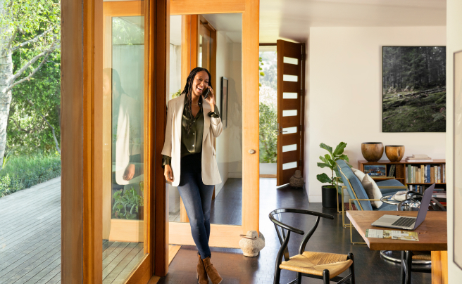 A Zillow Premier Agent smiling on a phone call inside a modern home.