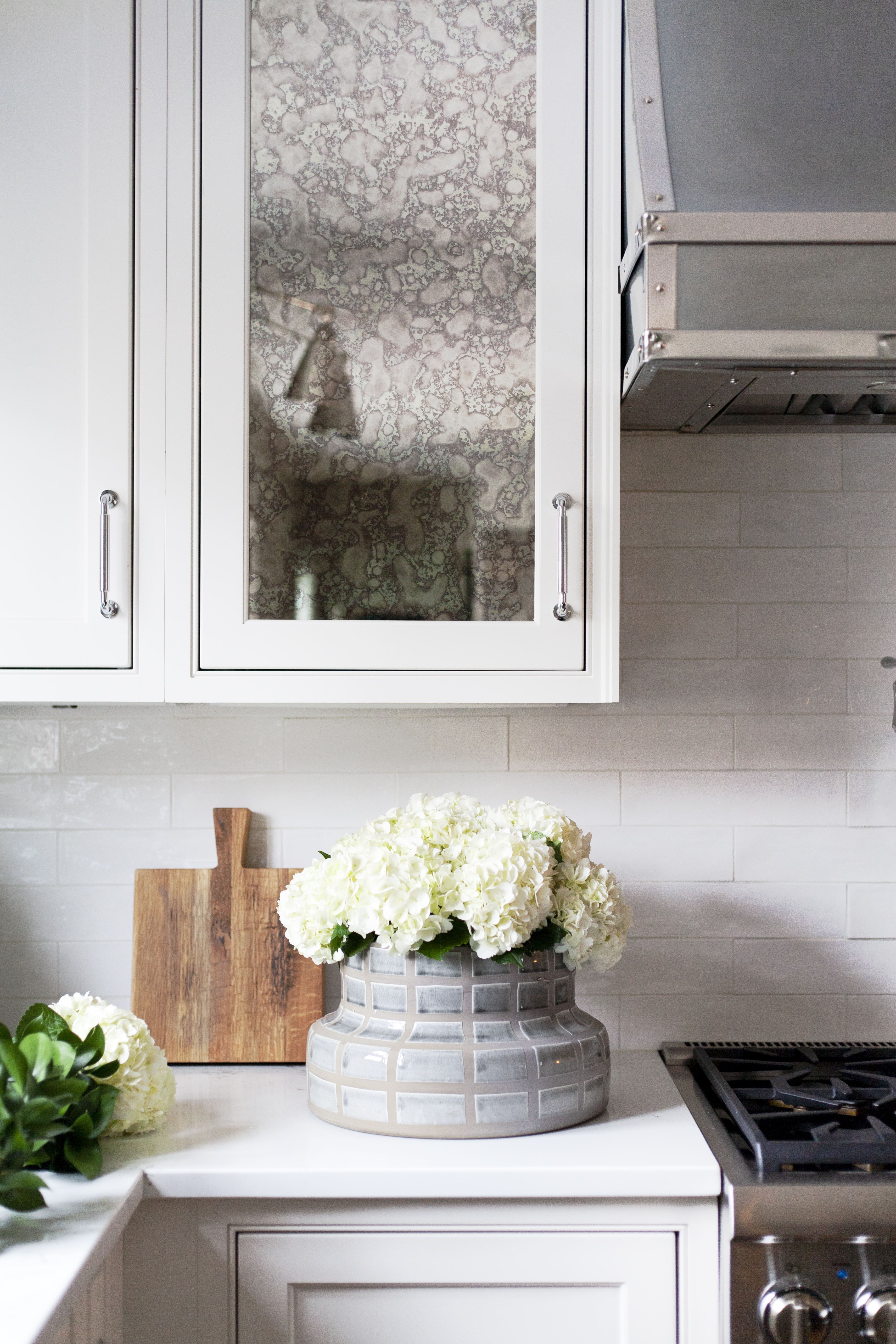 White kitchen with round vase and hydrangeas.