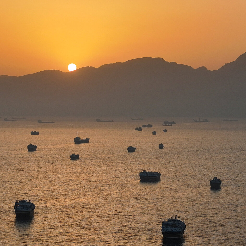 Dozens of small boats at anchor at sunset.