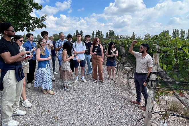 Students listen to a winemaking tour guide at a vineyard in Argentina.