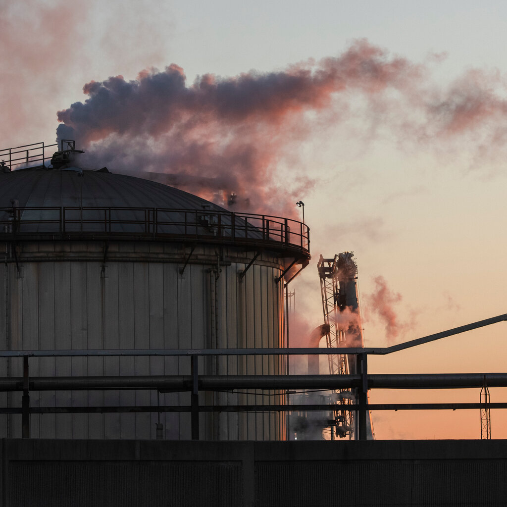 Smoke rises from an oil refinery. 
