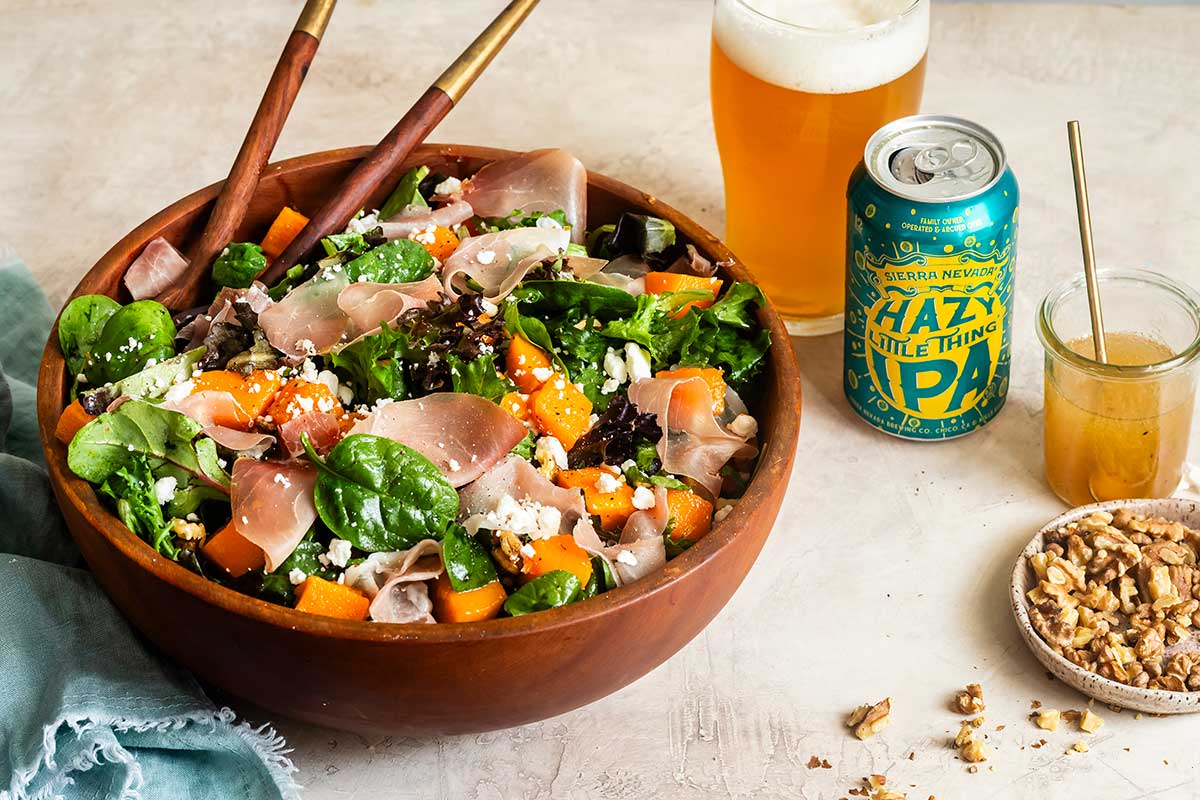 A bowl of holiday salad next to a can and glass of Hazy Little Thing IPA