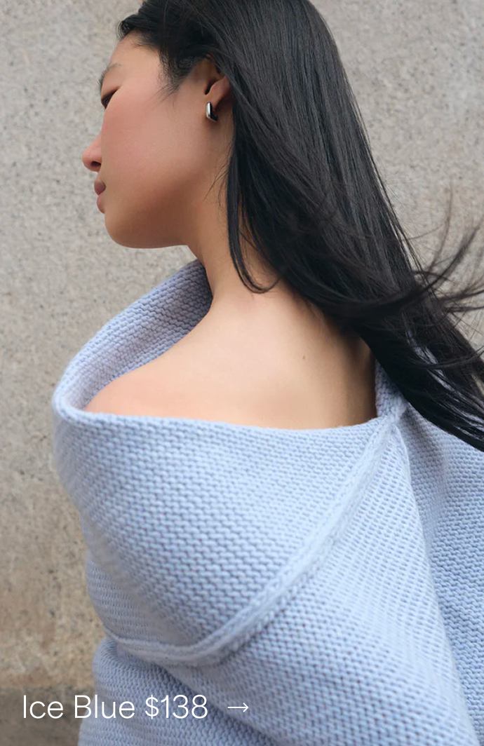 Side view of Xun wearing The Palmer Knit Top in Ice Blue off one shoulder, priced at $138 →.