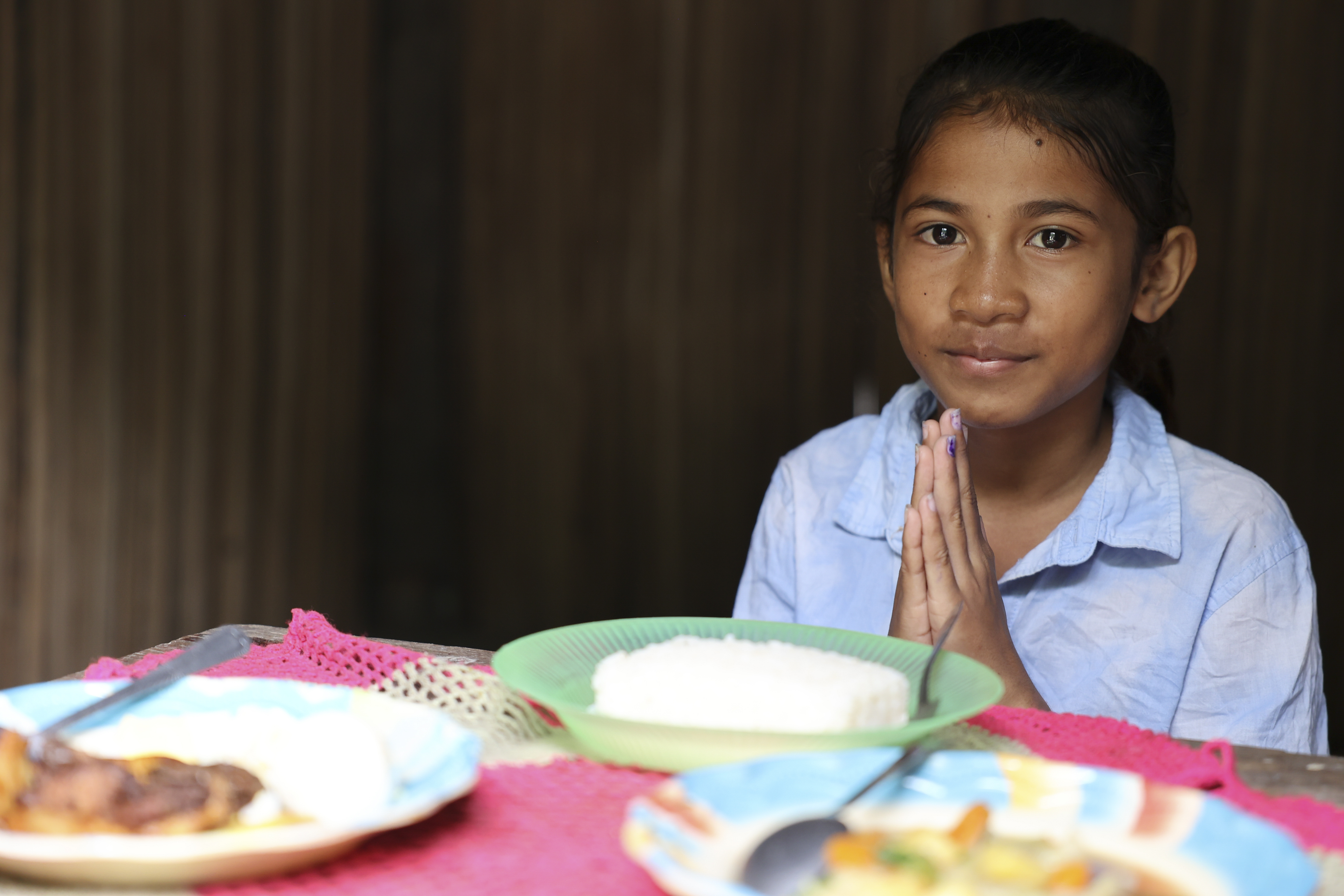A girl prays at the table before eating.