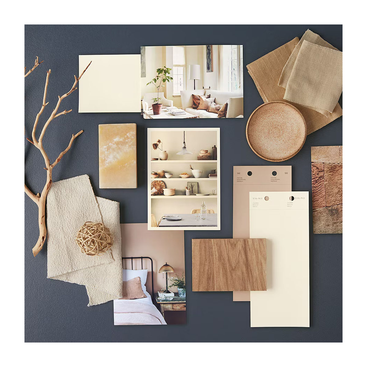 White and neutral paint chips, home interior photos and other natural accents lay atop a navy blue-painted surface.