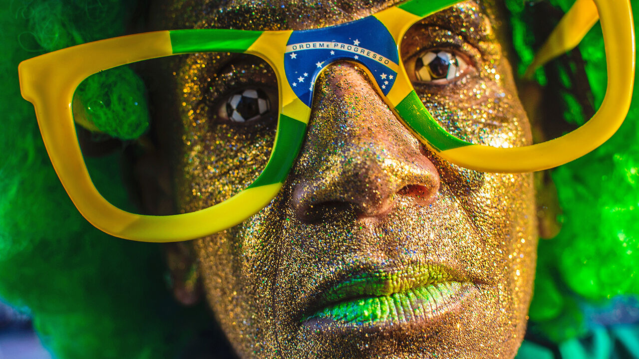 A Brazilian football supporters wears football contact lenses and Brazilain flag glasses. 