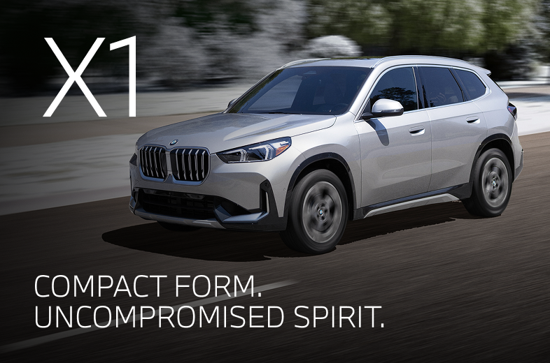 2026 BMW X1 driving down a winter road with snowy trees in the background