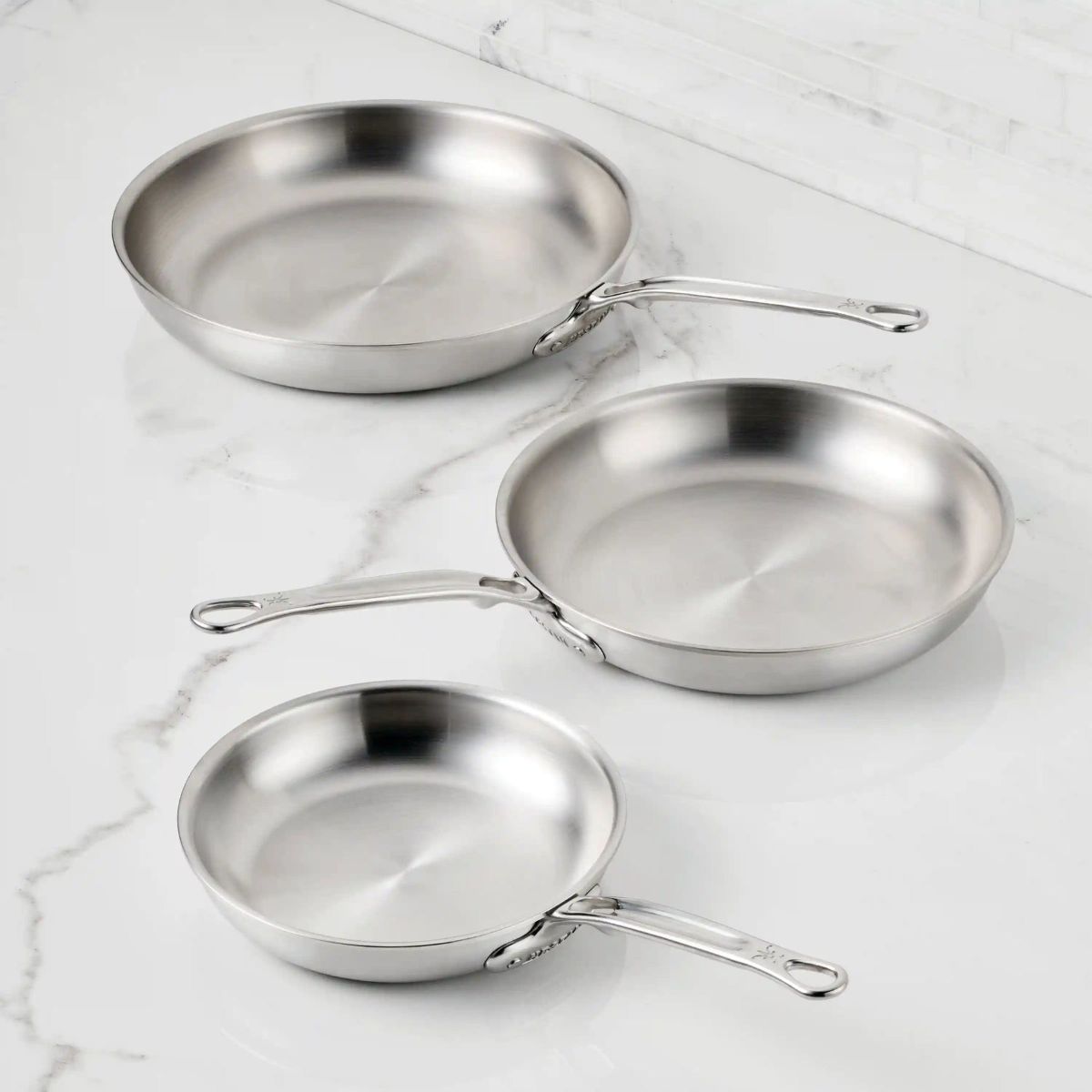 IMG: Thomas Keller Commercial Clad Stainless Steel Skillets on marble countertop