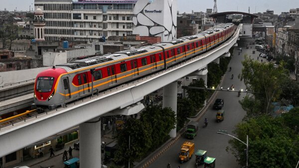 A metro train glides along an elevated track in Lahore as seen from an aerial view.