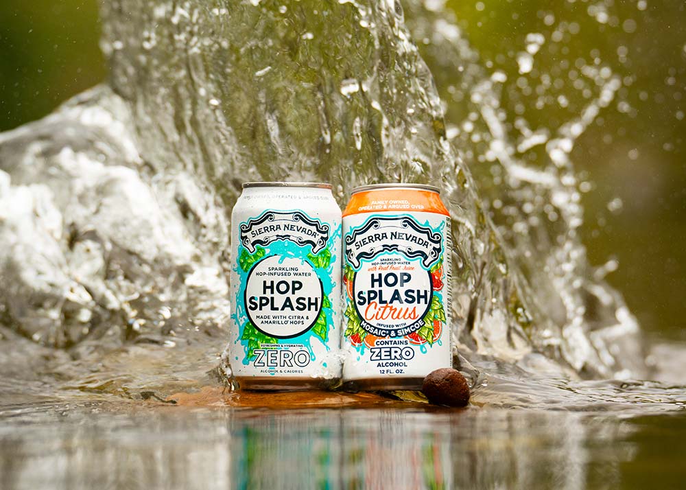 Two cans of Hop Splash surrounded by splashing water in a creek