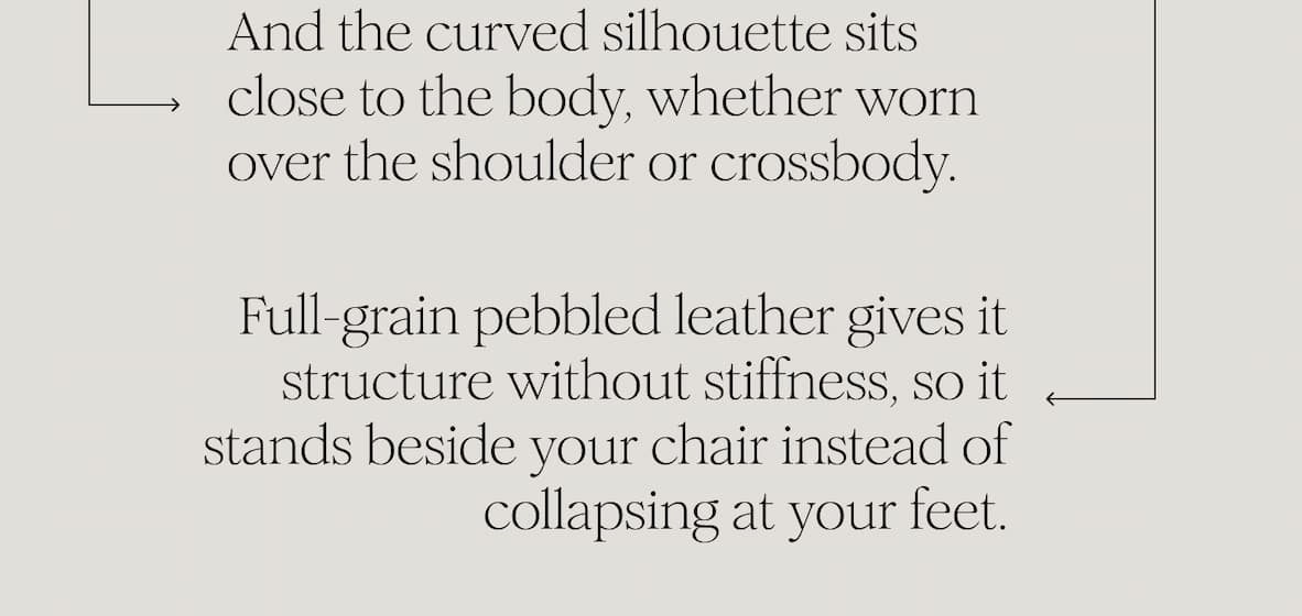 And the curved silhouette sits close to the body, whether worn over the shoulder or crossbody. Full-grain pebbled leather gives it structure without stiffness, so it stands beside your chair instead of collapsing at your feet.