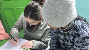one student writes on paper while another watches