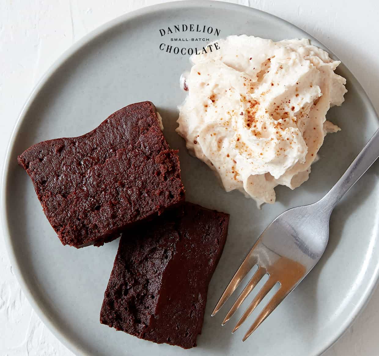 Two slices of our Tokyo Gâteau next to a dollop of whipped cream. 