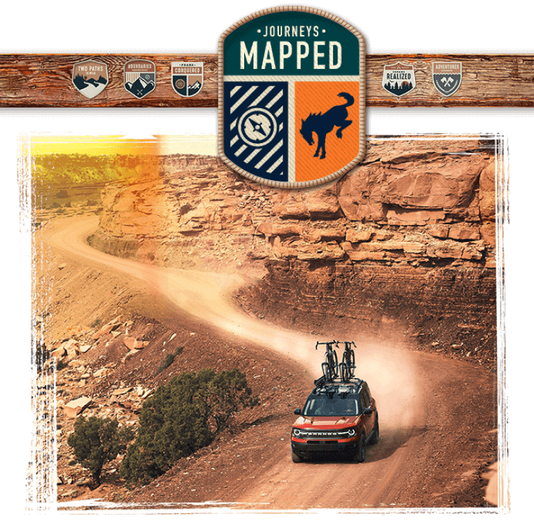 A Bronco&reg; Sport SUV with two bicycles on the roof being driven in a desert landscape, with a &ldquo;Journeys Mapped&rdquo; badge placed at the top of the image