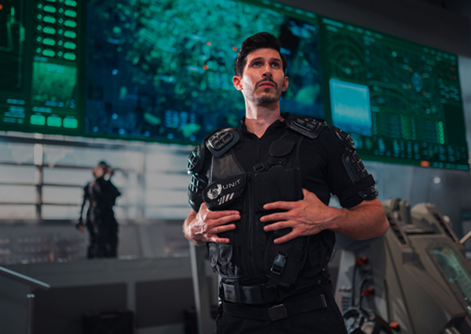 Christofer Ibrahim, played by Alexander Devrient, stands in a UNIT control room