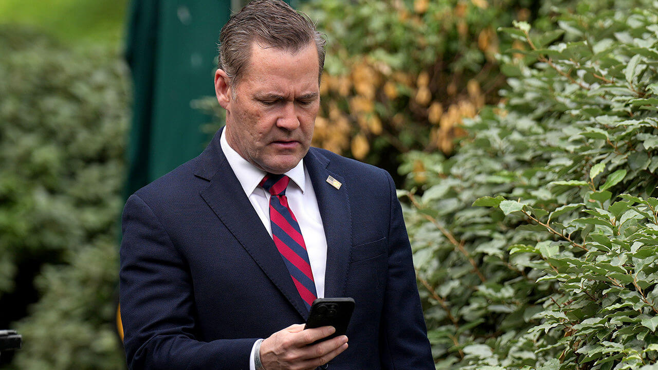 Michael Waltz looks at his phone at the White House