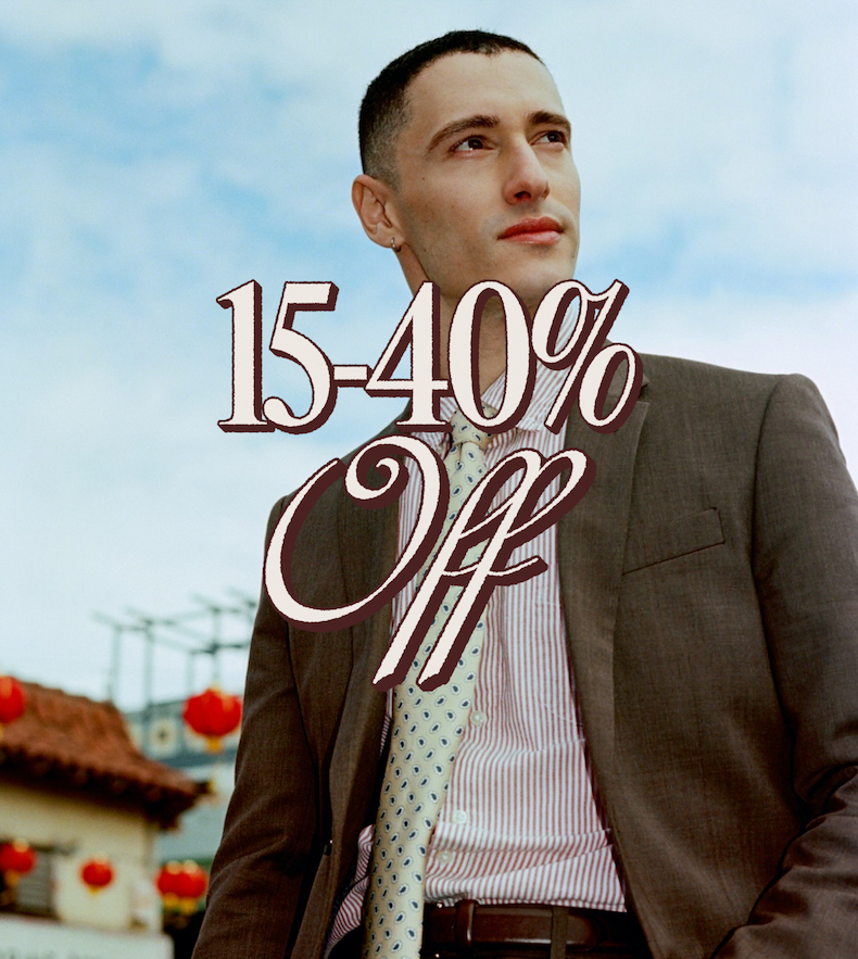 The Black Tux. 15–40% Off. Man in a brown suit with patterned tie looking off into the distance.