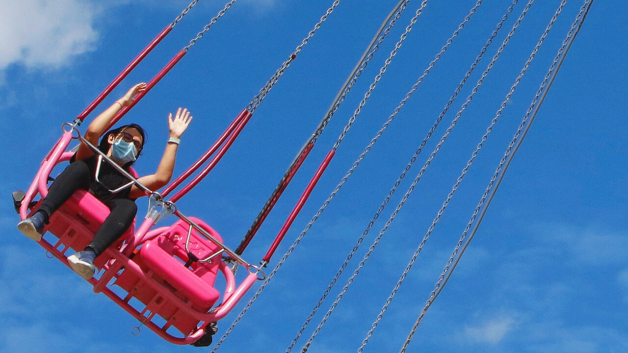 A woman wearing a protective mask takes a ride on a carousel in Paris, France, July 10th 2020