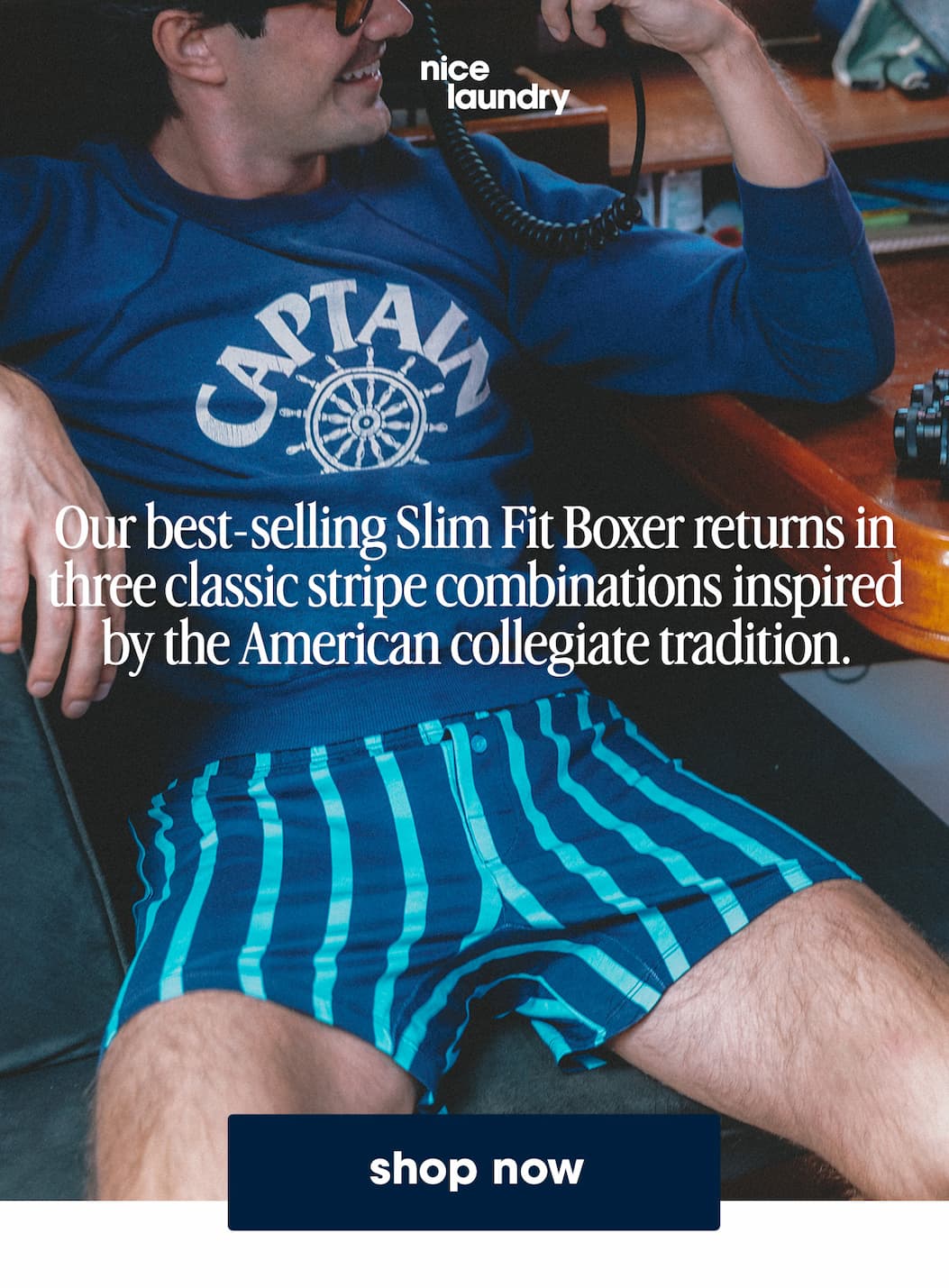 Man sitting inside boat wearing blue sweat shirt and blue stripe slim fit boxers. Text on image says " our best selling slim fit boxers returns in three classic stripe combinations inspired by the American collegiate tradition