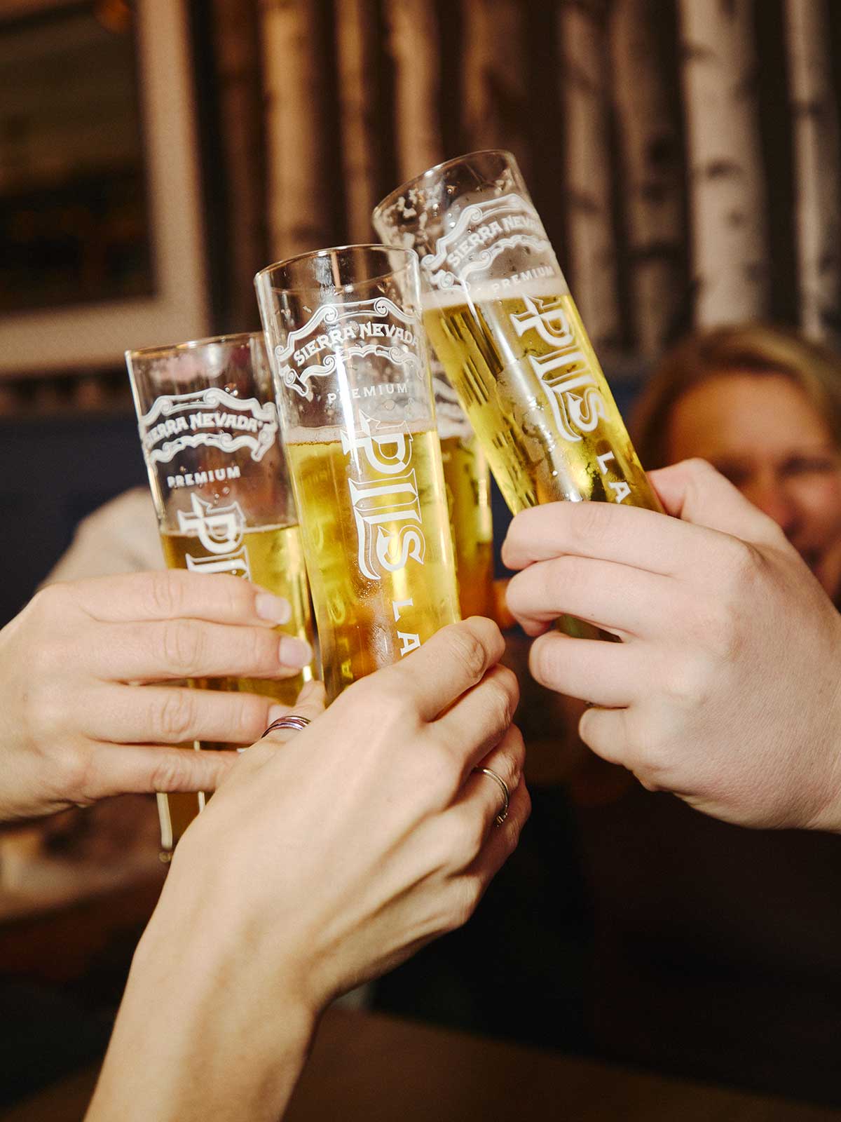 Three friends talking and holding glasses of Sierra Nevada PILS