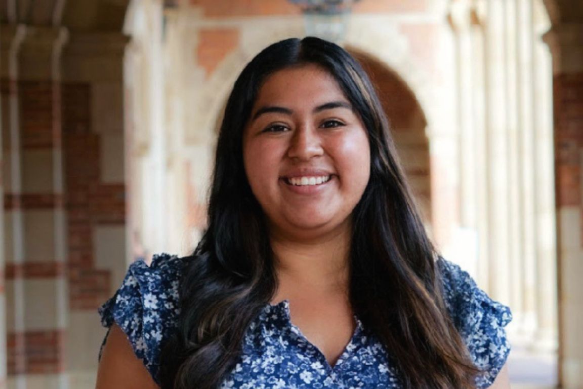 Head-and-shoulders photo of Citlali Rodriguez, in a blue floral-print top, standing in front of UCLA archway