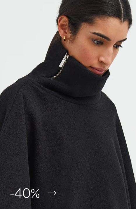 Sam in The Avery - a black high-neck sweater with side zipper detail on the collar.