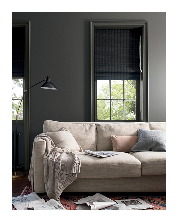 A dark gray painted living room wall with matching window trim, behind a beige sofa.