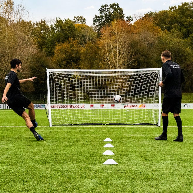 Two players on an artificial pitch training using the FORZA 12 x 6 ProFlex Goal.