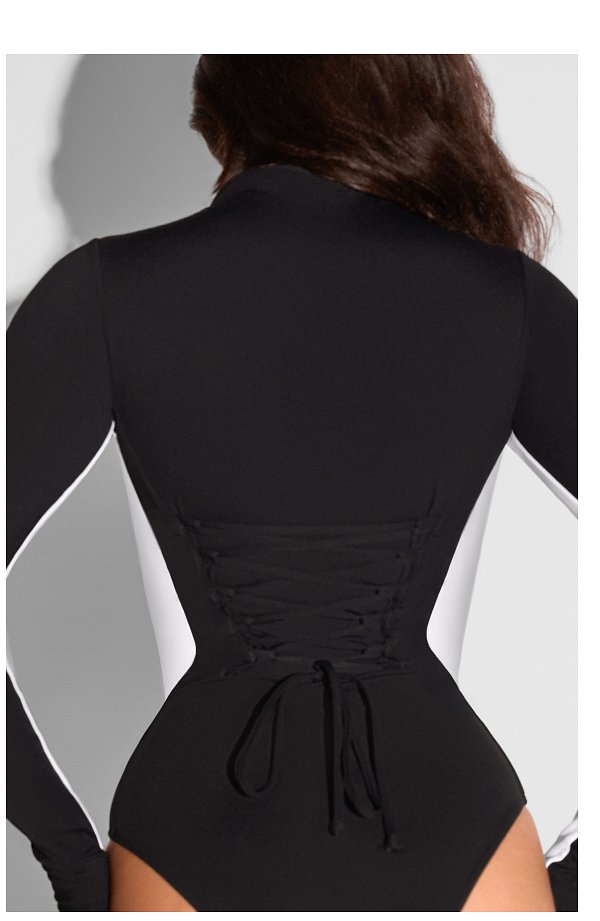 Back view of a black and white long-sleeve swimsuit with lace-up detail.
