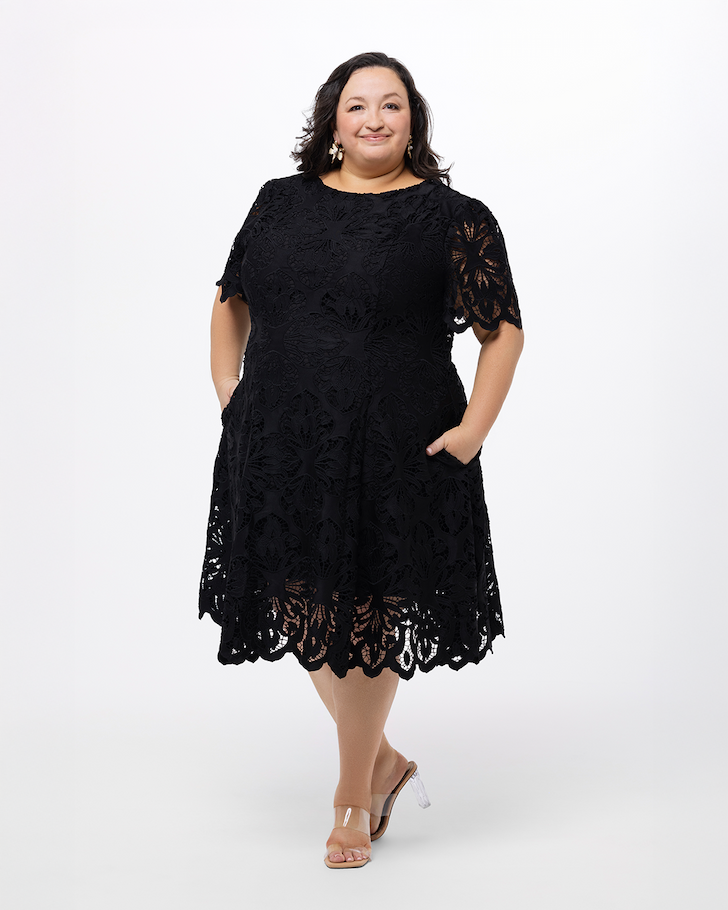 Woman wearing a short, black, lace dress with short sleeves.