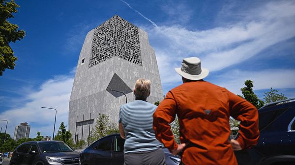 Pedestrians stand along Stony Island Avenue as they look at the Obama Presidential Center 