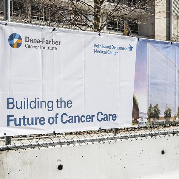 Construction barricade with scrim graphics announcing Future of Cancer Care