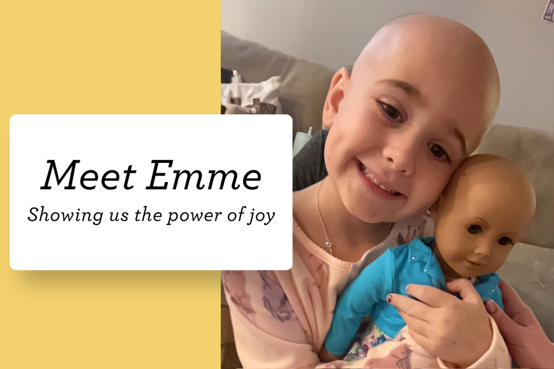 Meet Honored Kid Emme, smiling and holding her bald doll, a touching reflection of the joy and strength she carries through treatment.