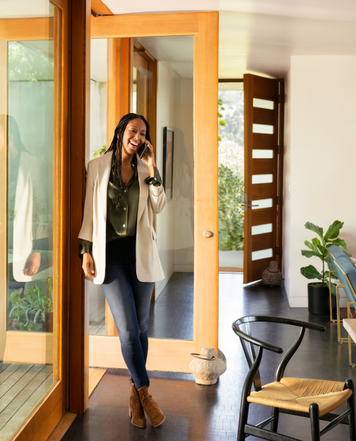 A Zillow Premier Agent smiling on a phone call inside a modern home.