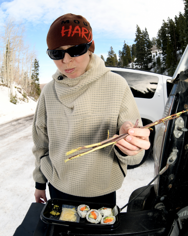 A snowboarder eating sushi and wearing the Women's Summit Grid™ Big Grid Hoody