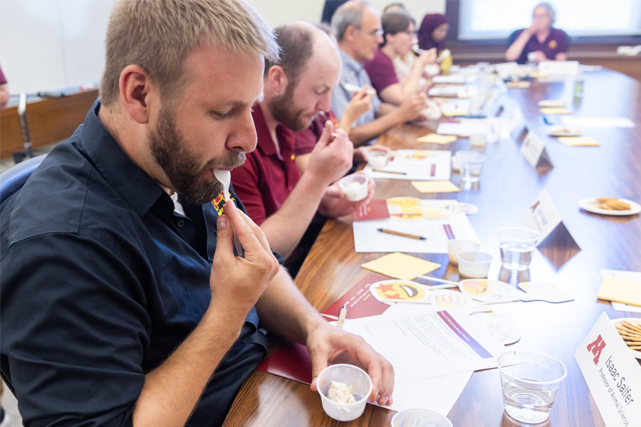 A man takes a bit of ice cream while seated at a table with others doing the same.