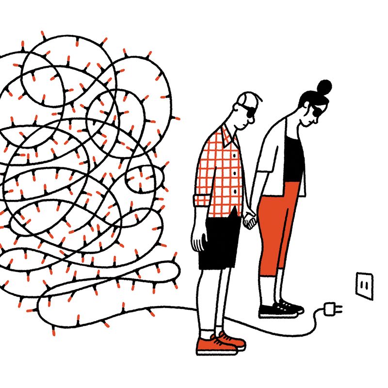 A couple looking at an unplugged string of fairy lights.