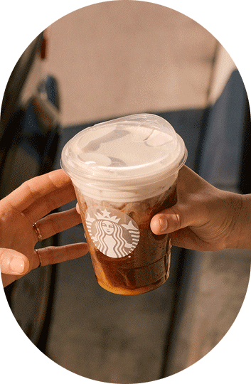 Someone hands an iced Starbucks coffee drink to a friend.