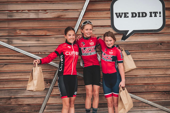 Three young riders on a podium with the words 'We did it!' in the background.