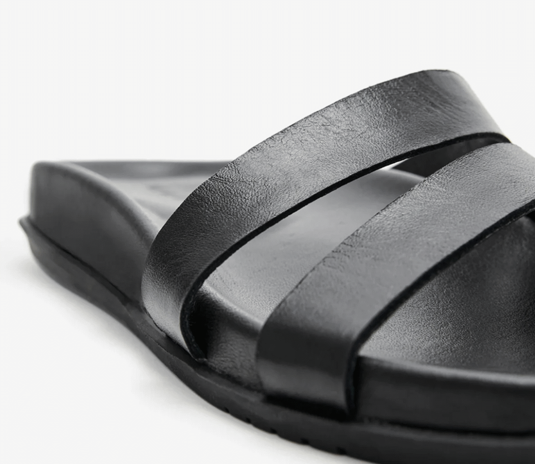 A close-up rotating view of The Kelis Sandals with double front straps, highlighting the smooth leather texture and cushioned sole.