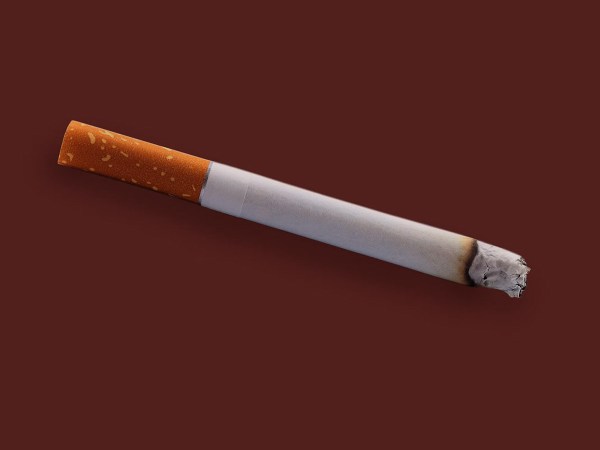 Burning cigarette on colored background.